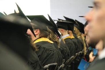 Graduation, graduates sititng in a row with back to camera and caps showing